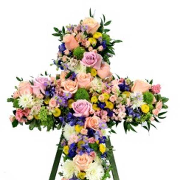 Floral cross on a standing easel with pastel roses and mixed blooms