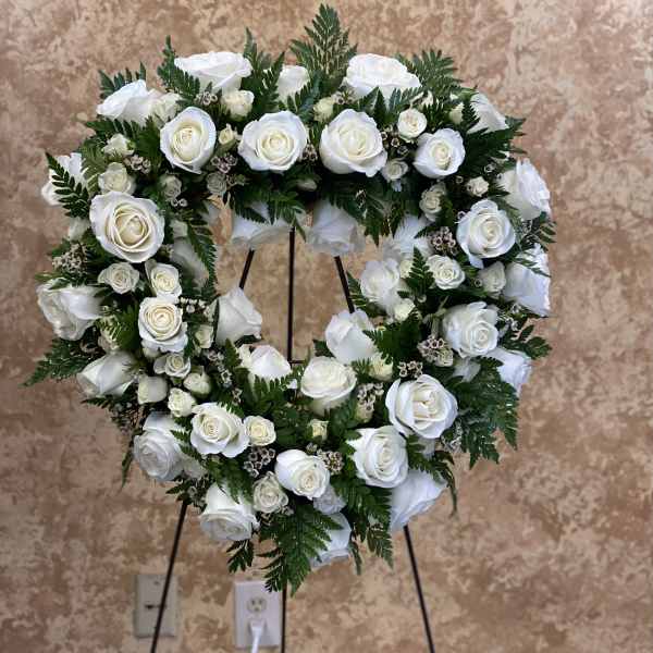 Heart-shaped wreath of white roses on a stand