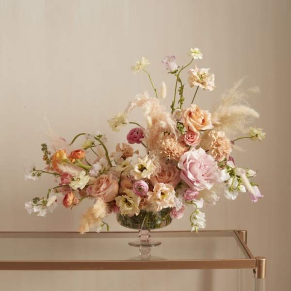 Pastel floral arrangement in a glass pedestal vase