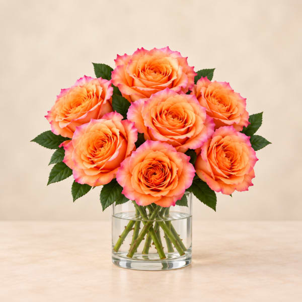 Orange and pink roses arranged in a clear glass vase