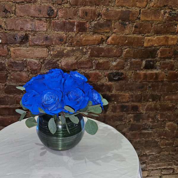 Blue rose bouquet in a dark glass vase on a round table