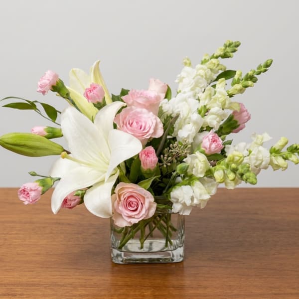 Pink roses and white lilies arranged in a clear glass vase