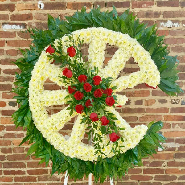 Large floral wreath with white flowers and red roses on a stand
