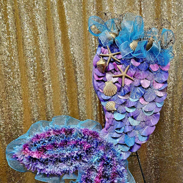 Purple and blue mermaid-shaped floral display with shells and starfish