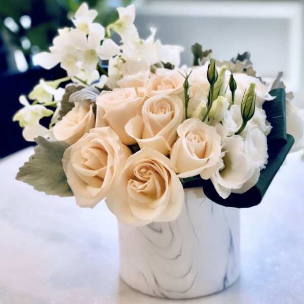 Peach roses and white flowers arranged in a white vase