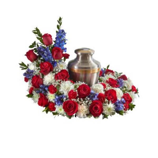 Cremation urn surrounded by red, white, and blue flowers in a circular sympathy arrangement
