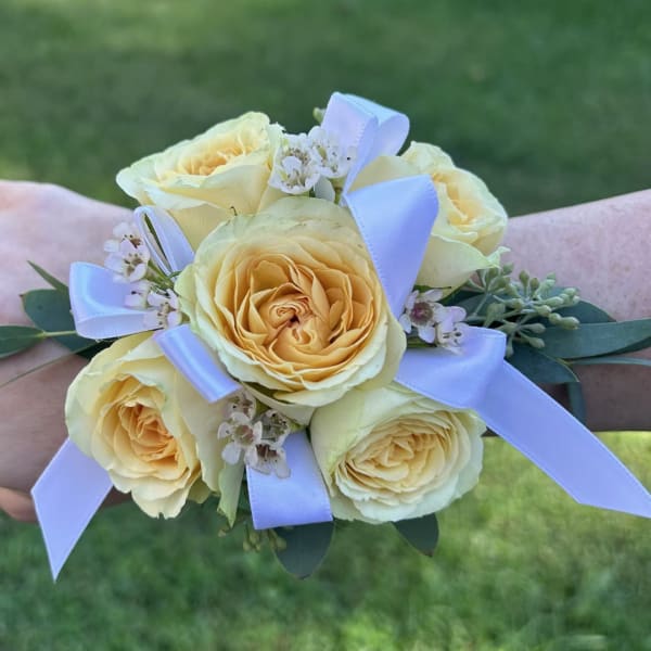 Small bouquet of pale yellow roses with white ribbon and tiny white flowers