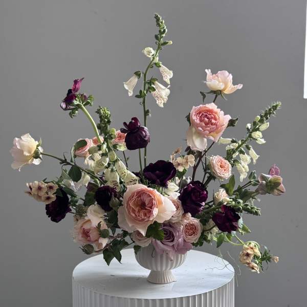 Mixed pink and purple floral arrangement in a white vase