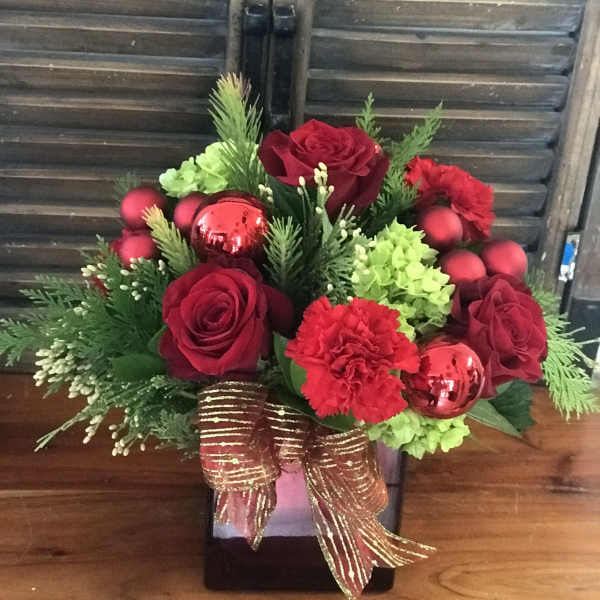 Red roses and carnations in a black vase with green accents and a gold ribbon