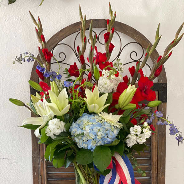 Mixed bouquet with lilies, hydrangea, and red gladiolus in a glass vase