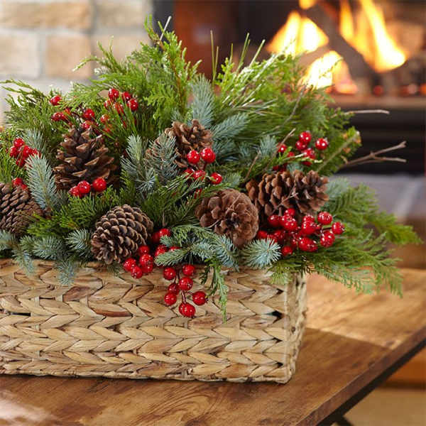 Pine and berry arrangement in a woven basket with pinecones