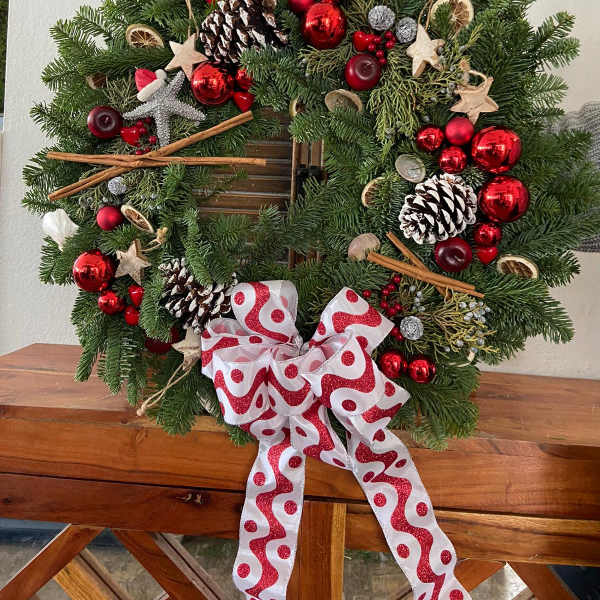 Christmas wreath with pinecones, red ornaments, and a patterned bow