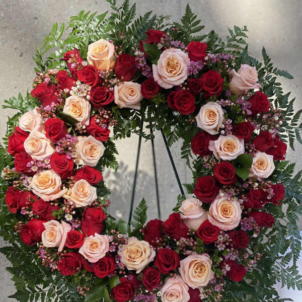 Heart-shaped wreath of red and blush roses on a stand