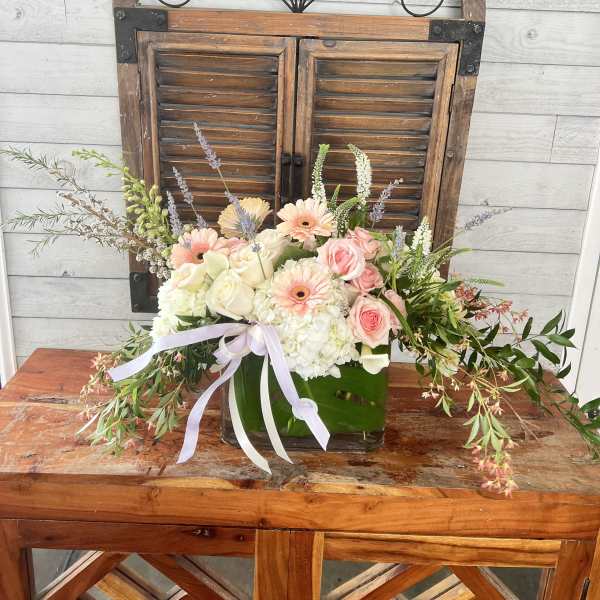 Pastel flower arrangement in a glass vase with a ribbon bow