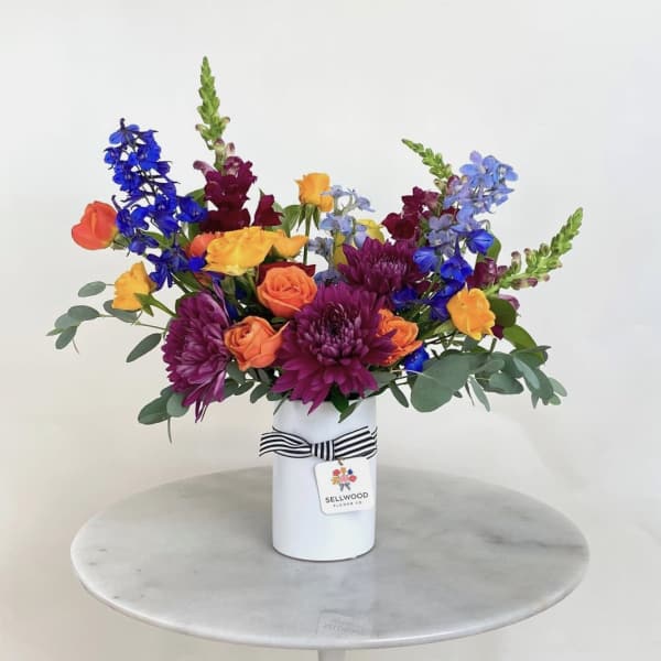 Colorful mixed bouquet in a white vase with a striped ribbon