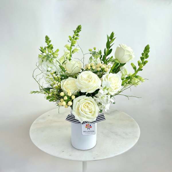 White rose arrangement in a white vase with black ribbon