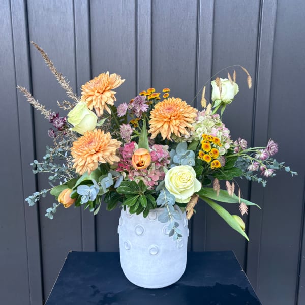 Mixed peach and white flowers arranged in a pale vase