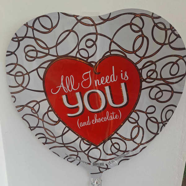 Heart-shaped balloon with the words "All I need is you (and chocolate)"