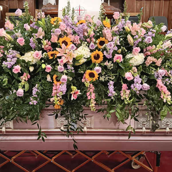 Large casket spray with pink and lavender flowers and sunflowers