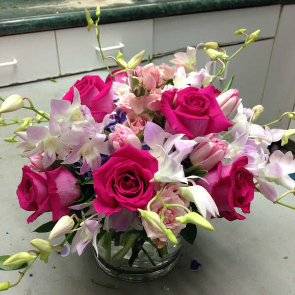 Pink roses and pale orchids arranged in a clear glass vase