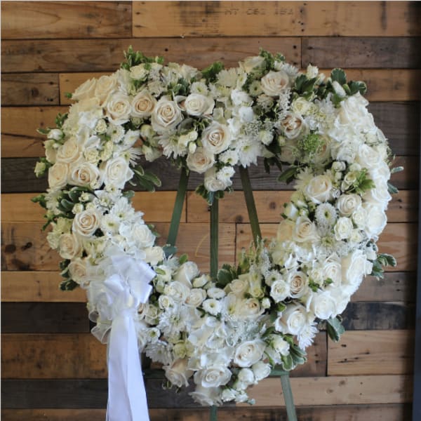 Heart-shaped wreath of white roses and daisies with a white ribbon