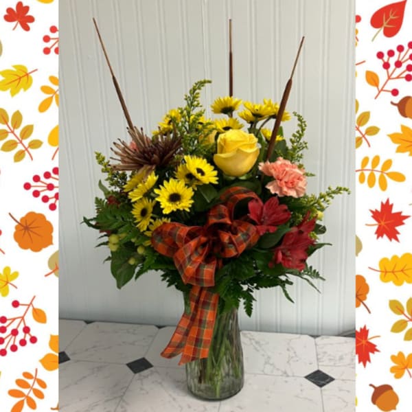Fall bouquet with yellow roses and daisies in a glass vase