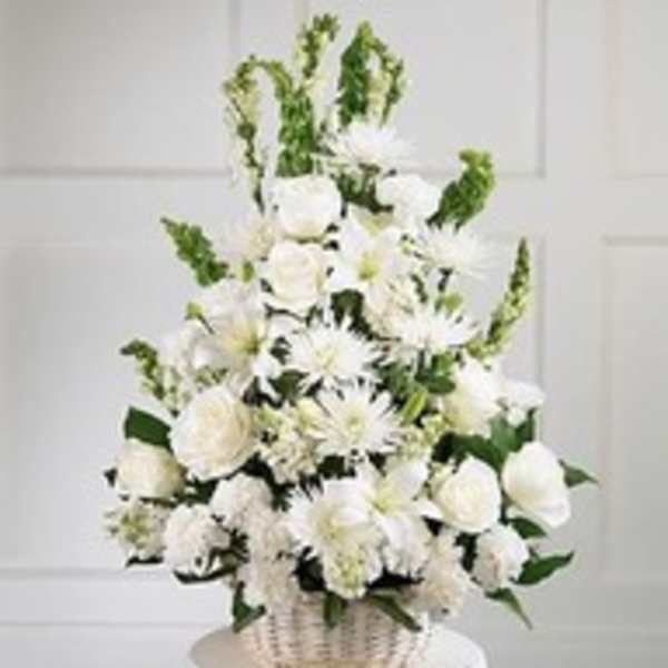 White floral arrangement in a wicker basket with tall green accents