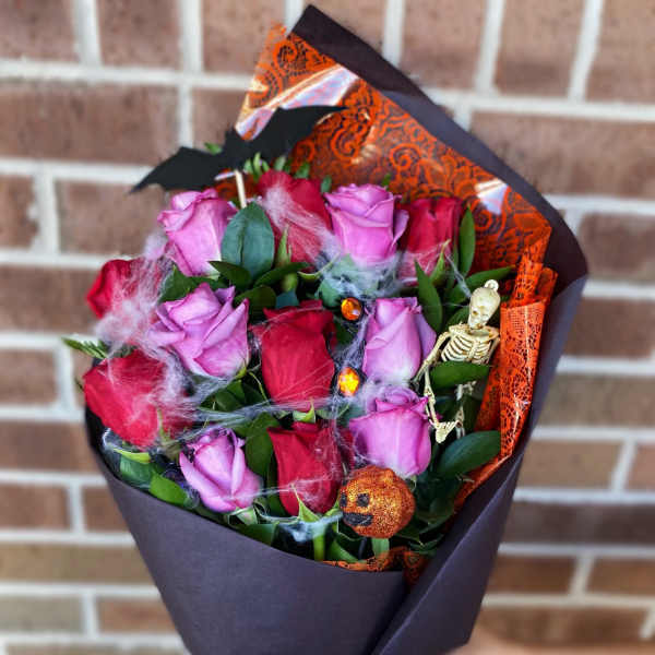 Bouquet of pink and red roses wrapped in black paper with orange ribbon