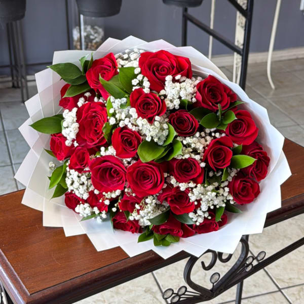 Bouquet of red roses with white baby's breath wrapped in white paper