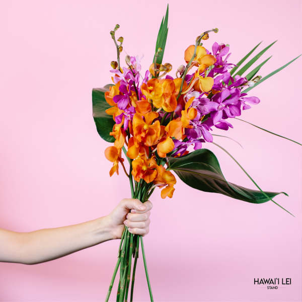 Handheld bouquet of orange and purple orchids with tropical leaves