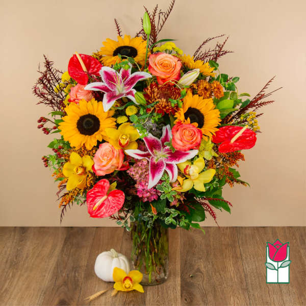 Mixed bouquet in a glass vase with sunflowers, roses, lilies, and anthuriums