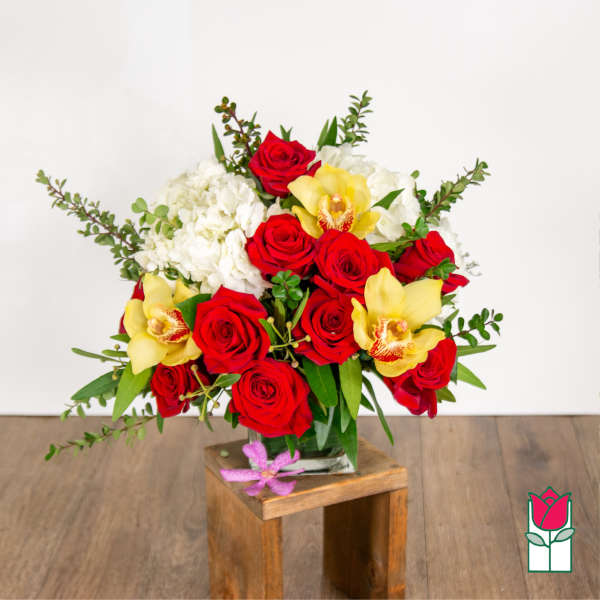 Bouquet of red roses, white hydrangeas, and yellow orchids in a glass vase