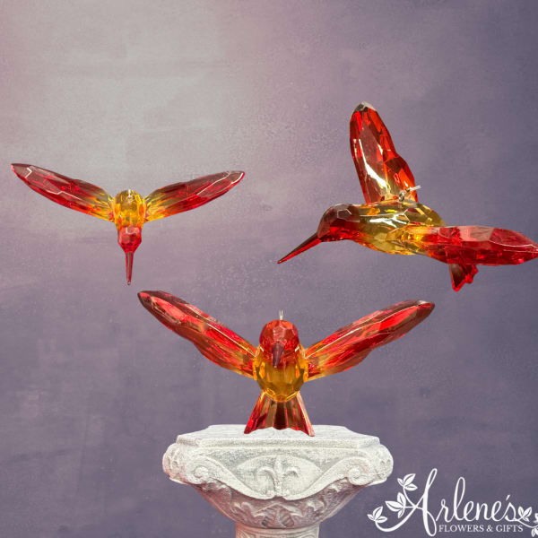 Three crystal hummingbird figurines on a decorative pedestal