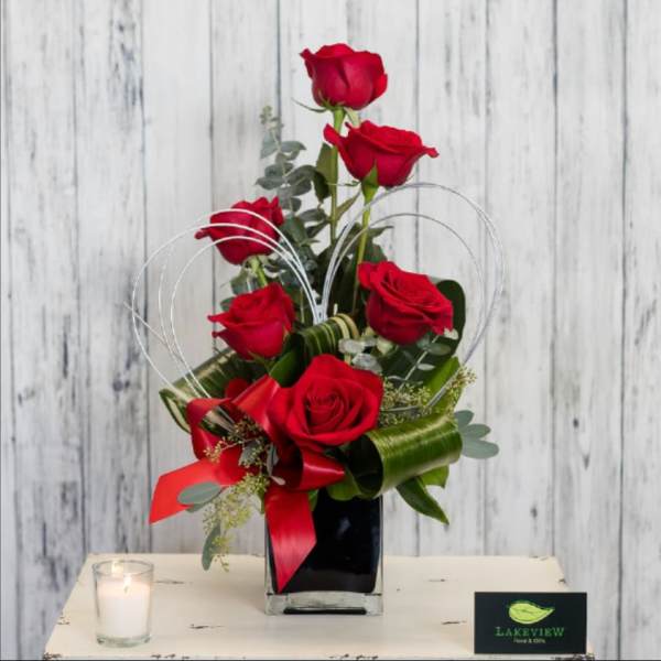 Red roses arranged in a black vase with a red ribbon