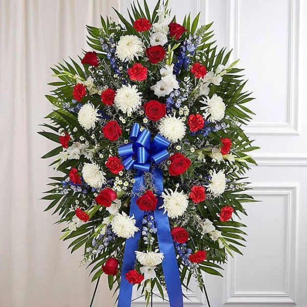 Standing floral spray with red, white, and blue flowers on a ribboned easel