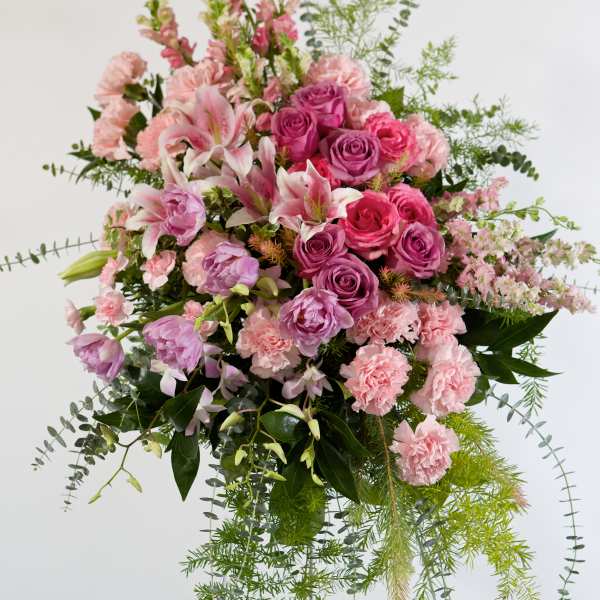 Pink and purple floral spray on a stand with trailing greenery