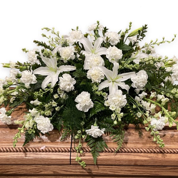 White floral casket spray with lilies and carnations