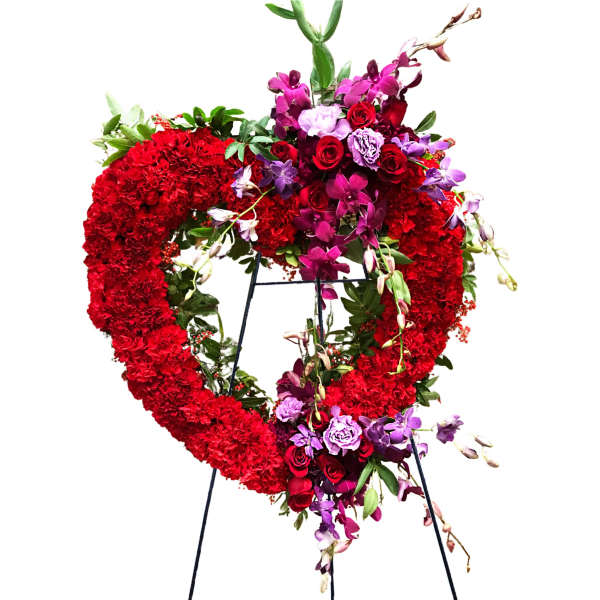 Heart-shaped floral wreath with red and purple flowers on a stand