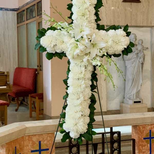 White floral cross on an easel in a church interior
