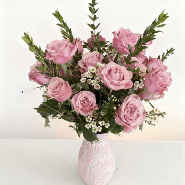 Pink roses arranged in a patterned vase with small white filler flowers