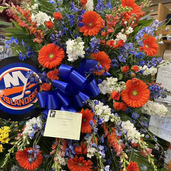 Large sympathy spray with orange gerberas, blue flowers, and white blooms