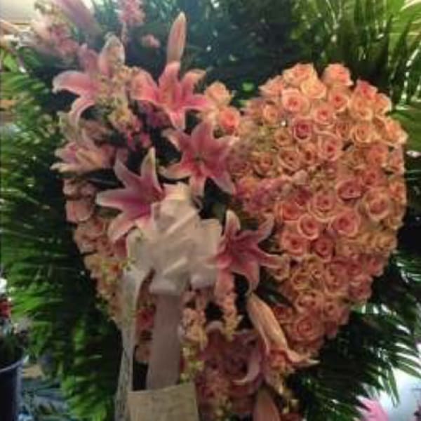 Heart-shaped floral tribute with pink lilies and roses