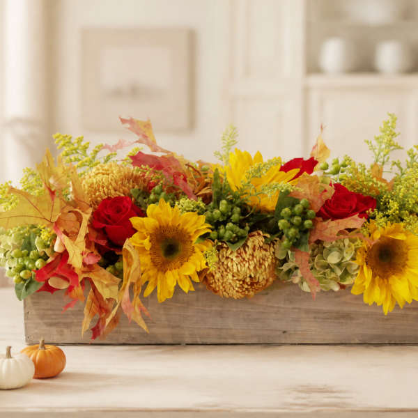 Autumn floral centerpiece with sunflowers and red roses in a wooden box