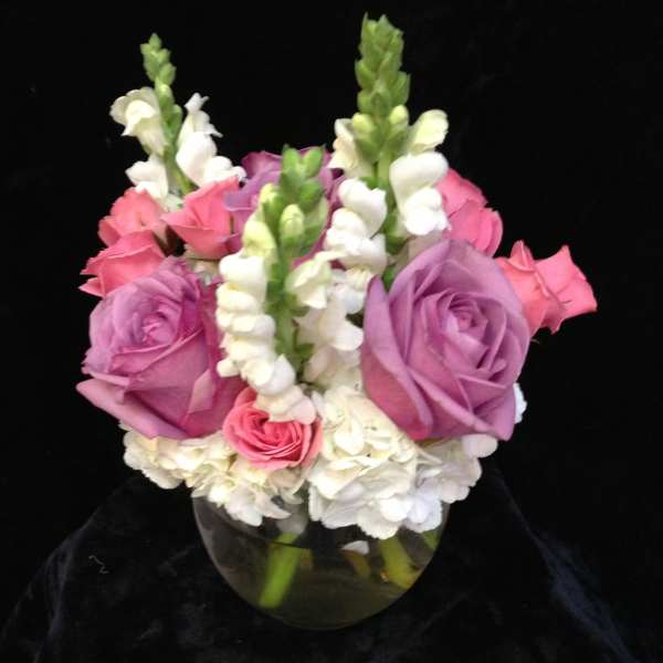 Pink and lavender roses with white snapdragons in a glass vase