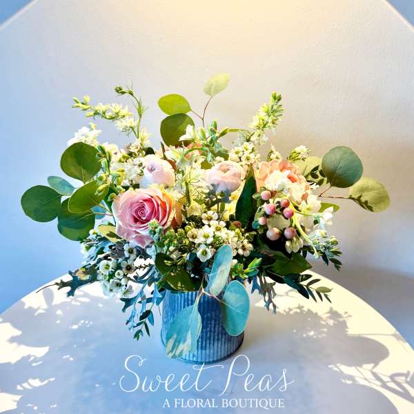 Pink roses and white blossoms arranged in a blue vase