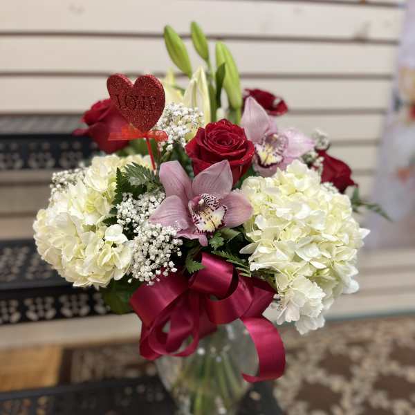 Bouquet of red roses, white hydrangeas, and pink orchids in a glass vase