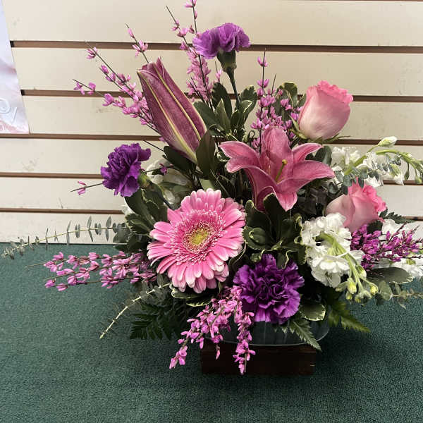 Pink and purple floral arrangement in a low container