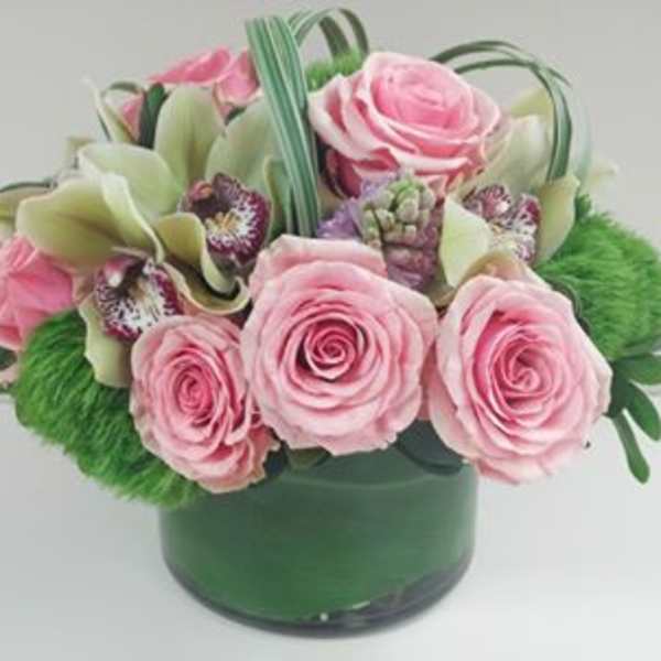 Pink roses and pale green orchids in a green vase