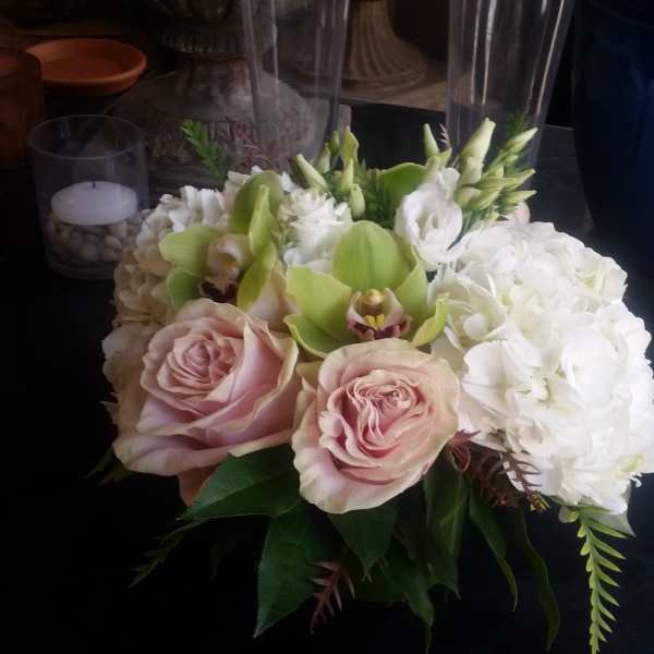 Pink roses and white hydrangeas with green orchids in a low arrangement