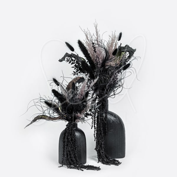 Two black vases hold dark dried floral arrangements.
